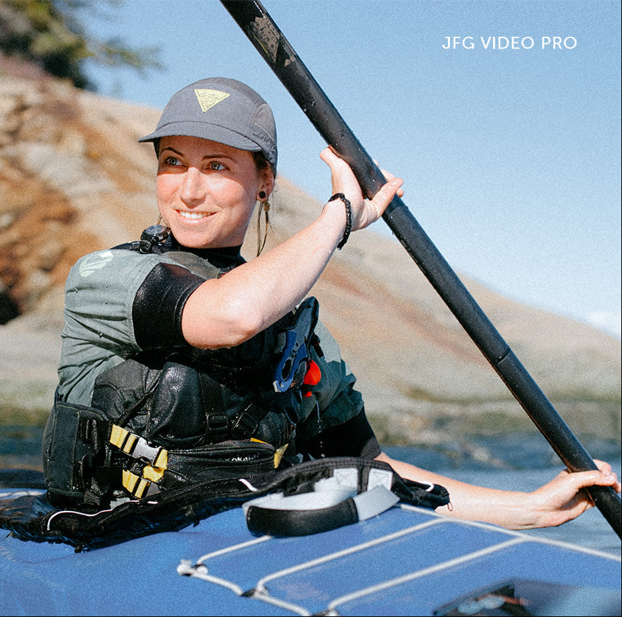 Person kayaking on a calm body of water with rocky terrain in the background